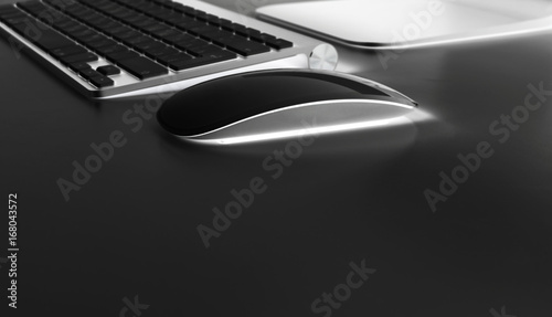 Workplace with computer and wireless keyboard and mouse on black table background..