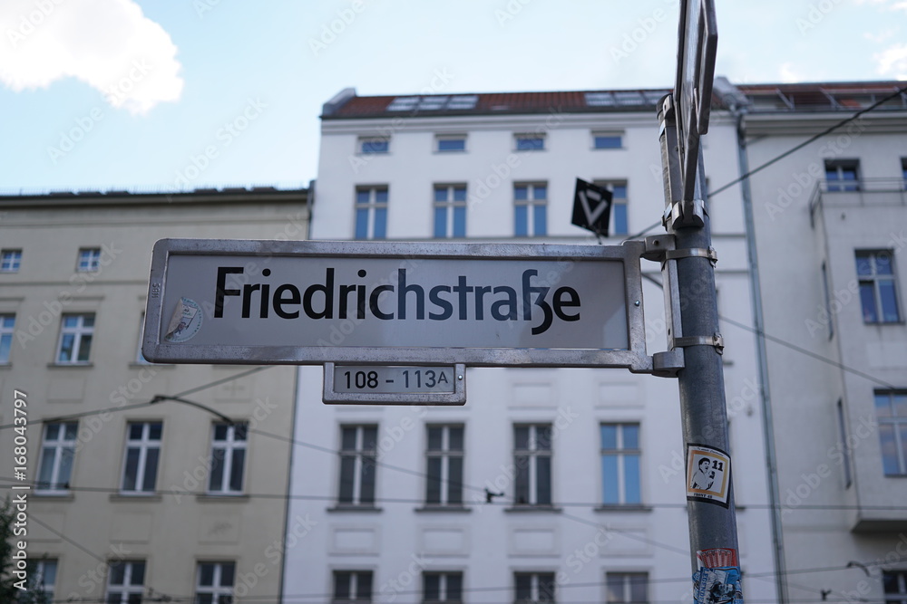 Berlin, Germany - August 13, 2017: Friedrichstrasse street sign name. The Friedrichstraße is a major culture and shopping street in central Berlin Berlin, Germany - August 13, 2017: Friedrichstrasse street sign name. The Friedrichstraße is a major culture and shopping street in central Berlin