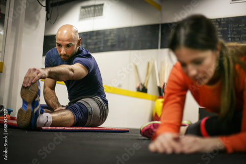 Friends in the gym. Two people stretching in the gym.