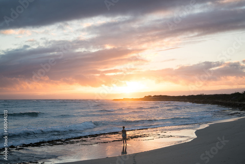 Rear view of woman standing on beach during sunset