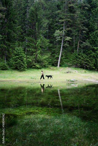 woman with dog walking along lake