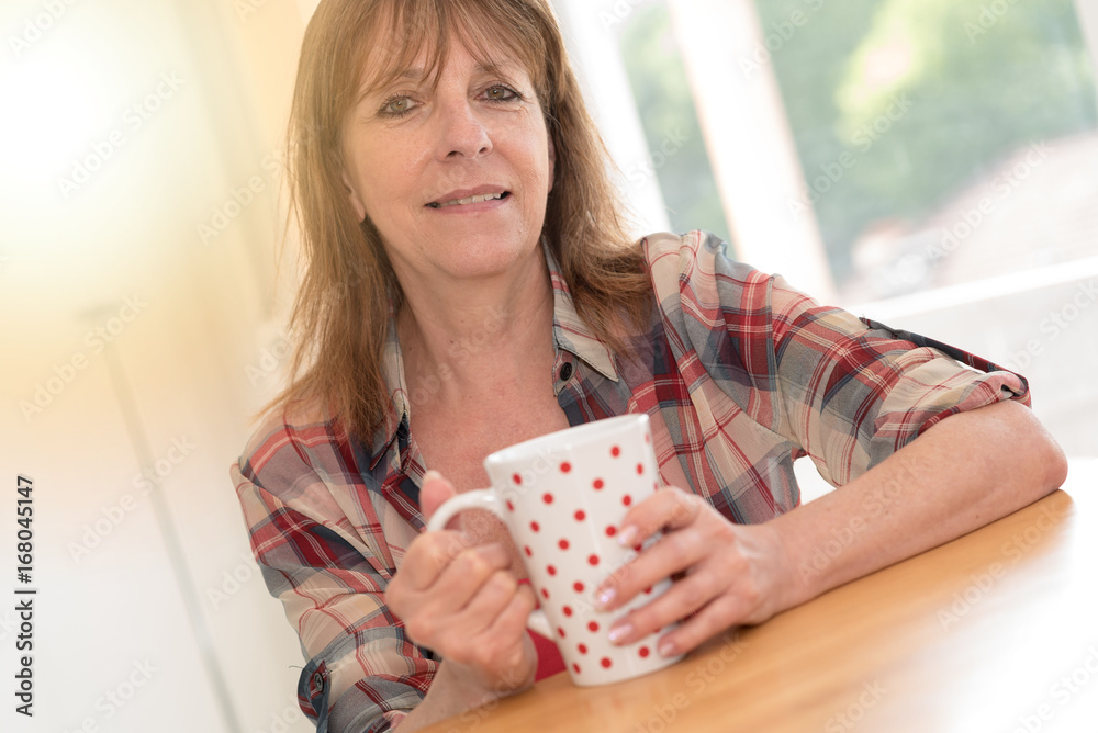 Portrait of mature woman smiling and holding a mug, light effect Portrait of mature woman smiling and holding a mug, light effect