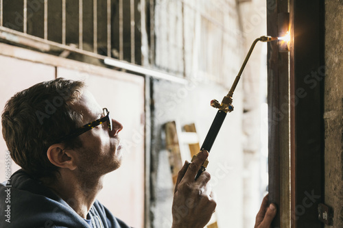Blacksmith brazing door hinges at construction site