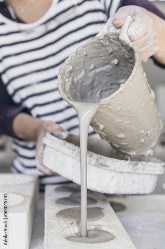 Closeup of hand casting ceramic slip from a jug