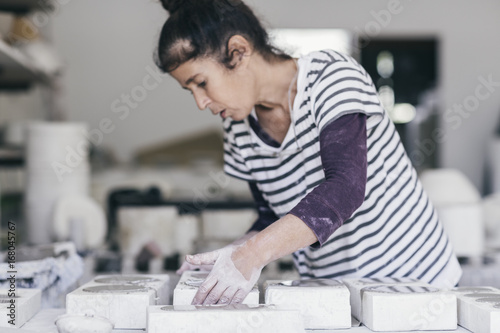Female ceramic artist arranging moulds in her studio