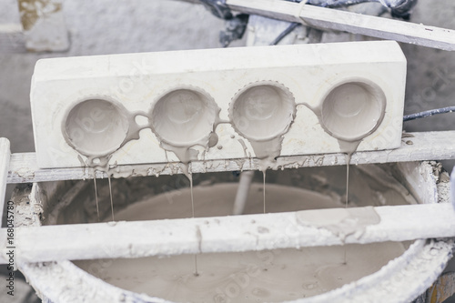 Ceramic clay moulds dripping over bucket of wet slip photo