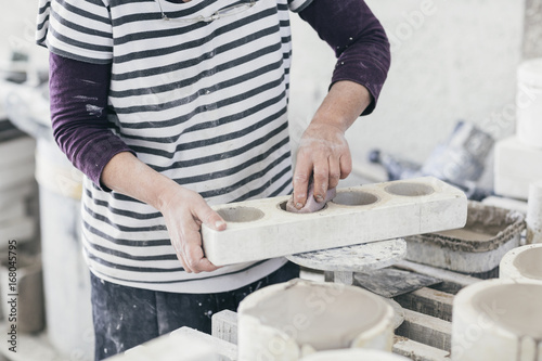 Hands of a ceramic artist cleaning wet moulds
