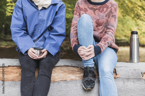 Closeup of two female friends drinking tea in the forest