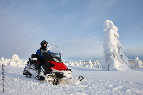 Man driving snowmobile in snowyfield in a sunny day. Lapland, Finland. photo