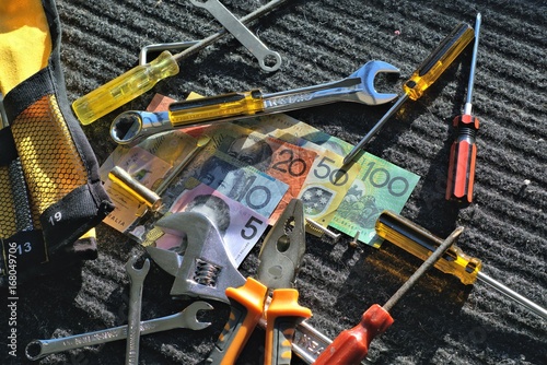 Australian dollar and Worker's tools on gray-black work mat outdoors in direct sunlight