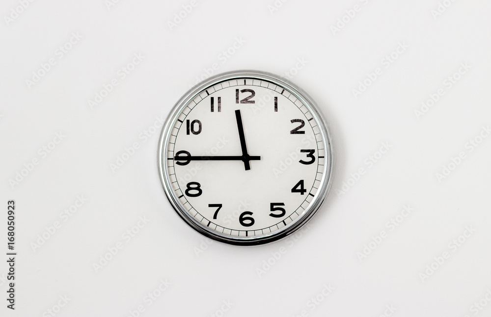 White Clock hanging on a white wall showing time 11:45