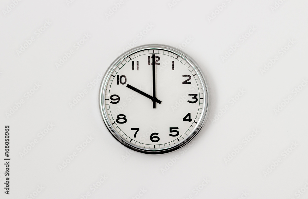 White Clock hanging on a white wall showing time 10:00 White Clock hanging on a white wall showing time 10:00
