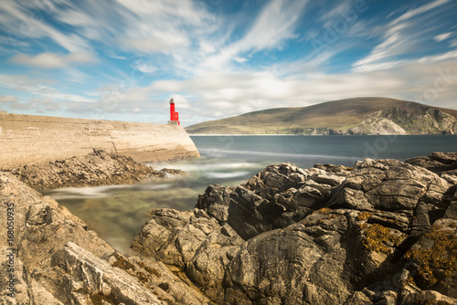 Small red lighthouse on a harbour sea wall 