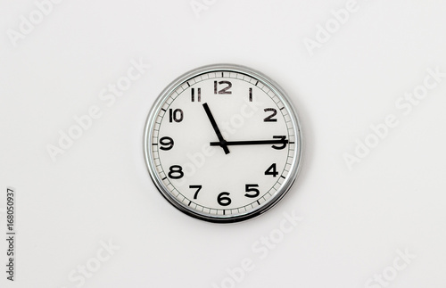 White Clock hanging on a white wall showing time 11:15