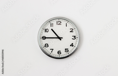 White Clock hanging on a white wall showing time 10:45