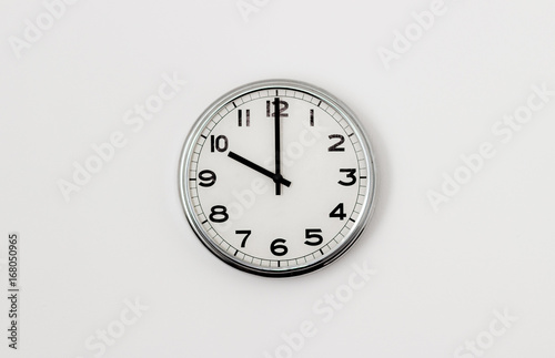 White Clock hanging on a white wall showing time 10:00