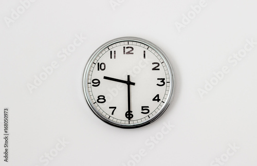 White Clock hanging on a white wall showing time 9:30
