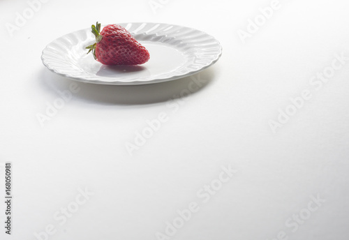 Isolated red strawberry on white plate on plain white background