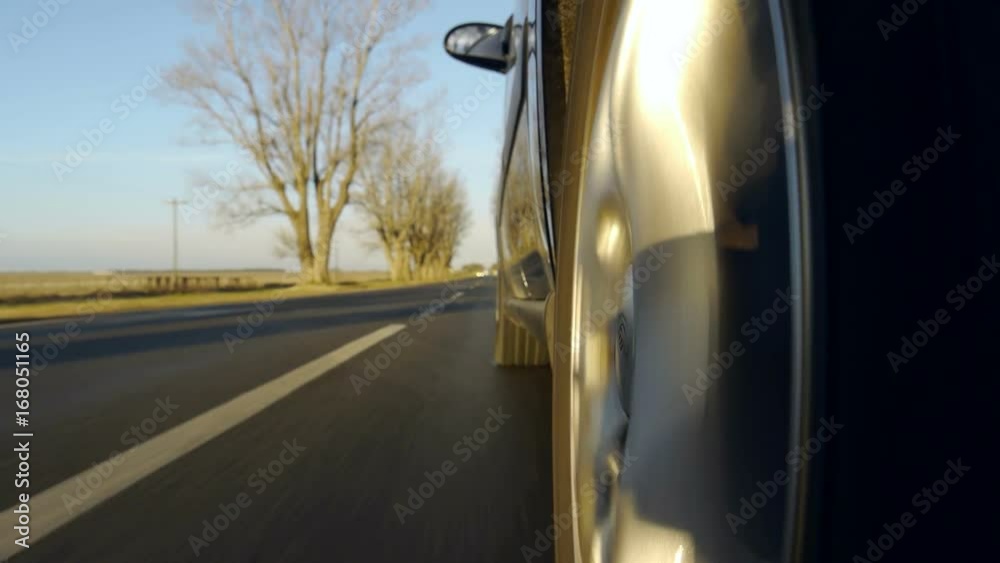 Driving a car on a country road. Wheel spinning POV - Point of View, day country side, sunset, fall / winter. Trees on the side. Slow motion speed