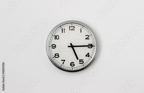White Clock hanging on a white wall showing time 5:15