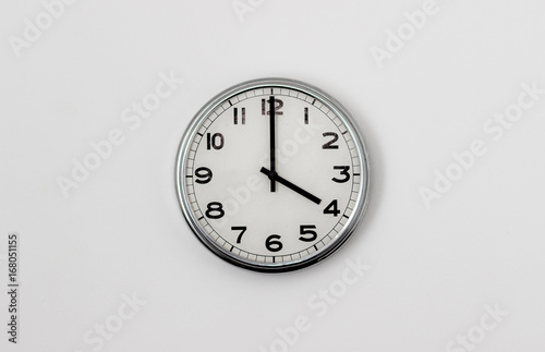 White Clock hanging on a white wall showing time 4:00