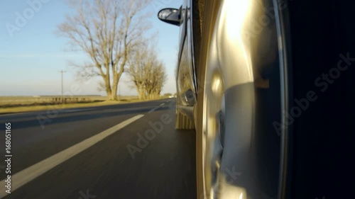Driving a car on a country road. Wheel spinning POV - Point of View, day country side, sunset, fall / winter. Trees on the side. Slow motion speed