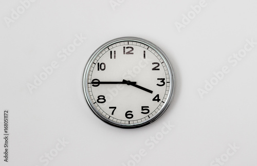 White Clock hanging on a white wall showing time 3:45