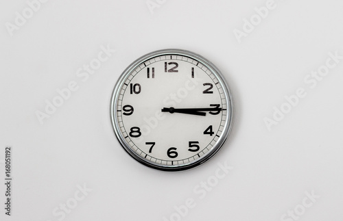 White Clock hanging on a white wall showing time 3:15