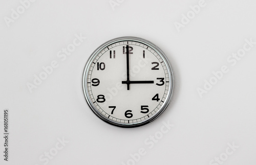 White Clock hanging on a white wall showing time 3:00