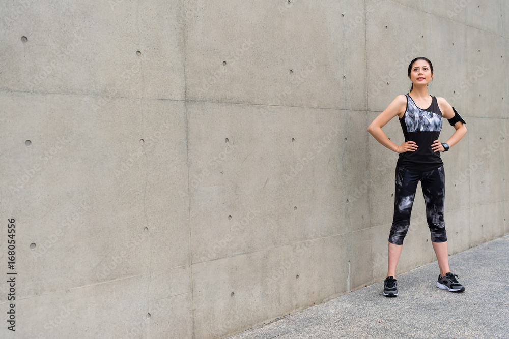 confident happy woman standing on gray wall