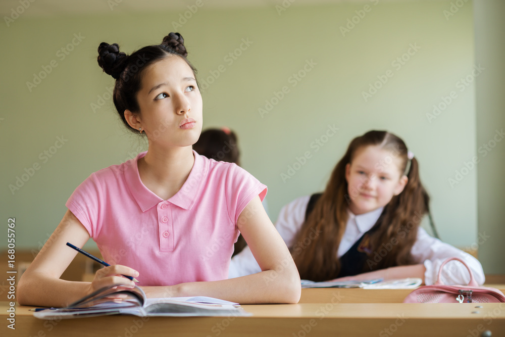 student thinks about the work,Girl holding a pencil and looking to the side student thinks about the work,Girl holding a pencil and looking to the side