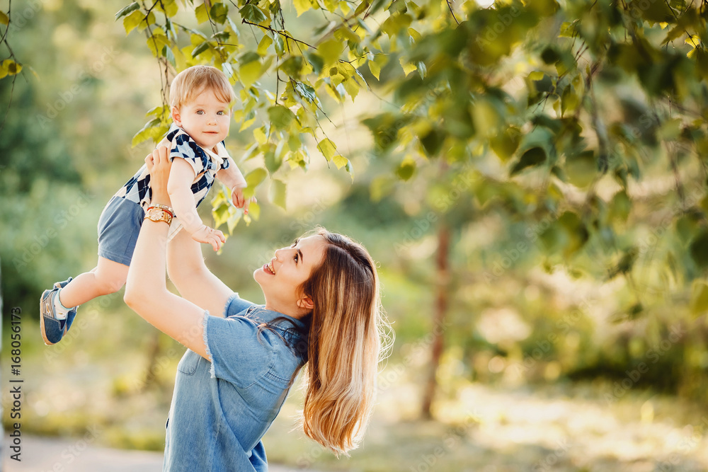 Naklejka premium Mom and little son are playing in the park. The boy smiles, laughs. Concept Mother's Day.