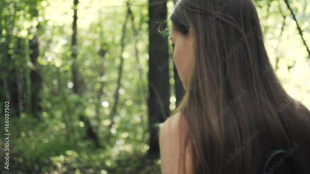 Beautiful woman hiker standing on forest trail and looking away. Female tourist on hike in nature. Beautiful woman hiker standing on forest trail and looking away. Female tourist on hike in nature.