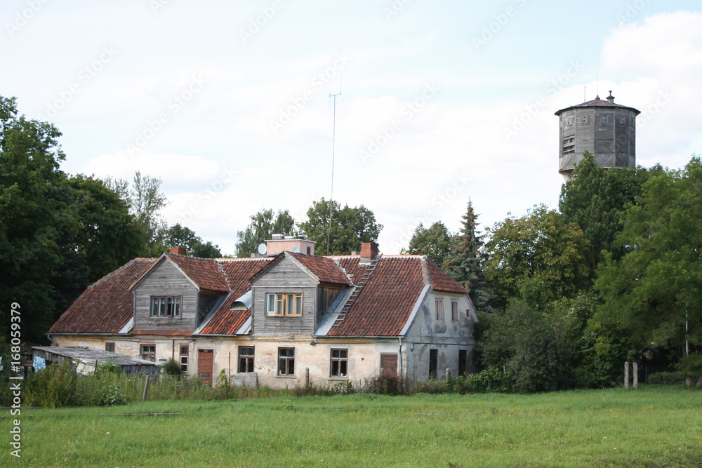 Old countryside view of old house and water tower with blue sky.
