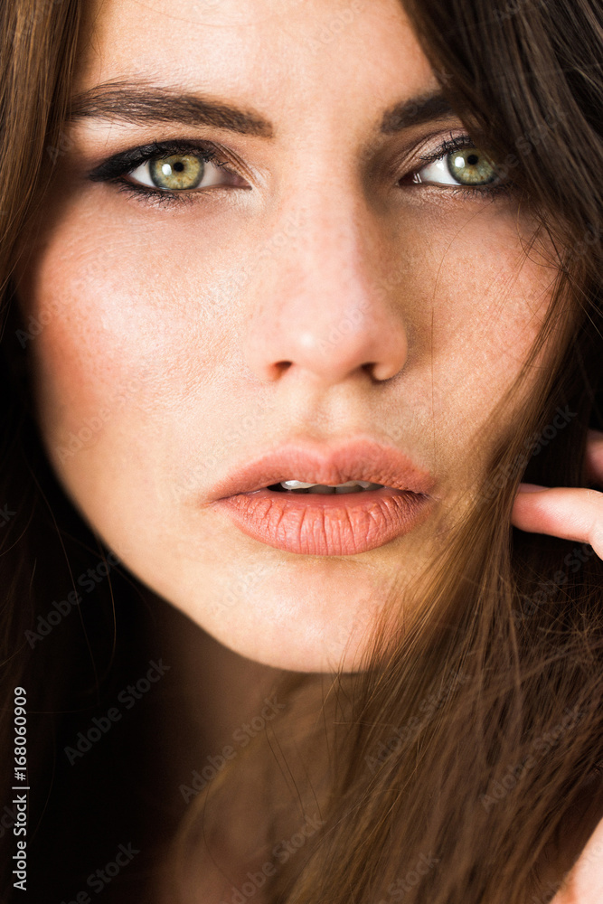 Stunning green-eyed woman sits before red flowers Stunning green-eyed woman sits before red flowers