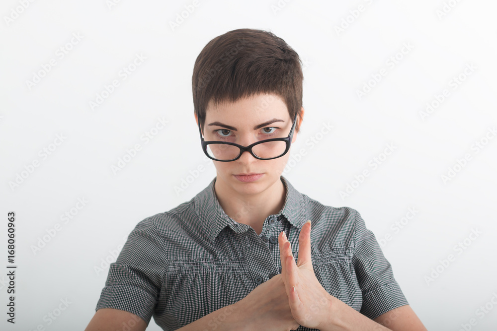 The portrait the young beautiful woman threatens with a fist on white background. The portrait the young beautiful woman threatens with a fist on white background.