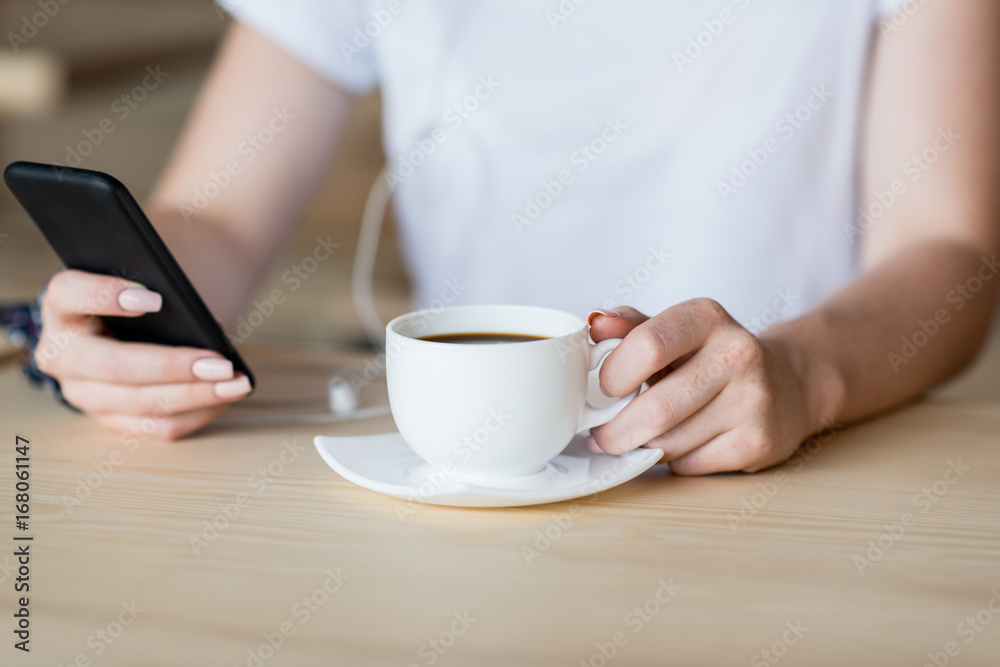 smartphone and cup of coffee in female hands smartphone and cup of coffee in female hands