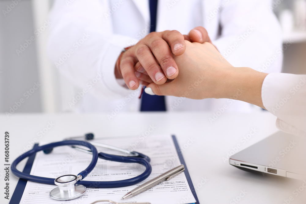 Friendly male doctor hold female arm in office during reception Friendly male doctor hold female arm in office during reception
