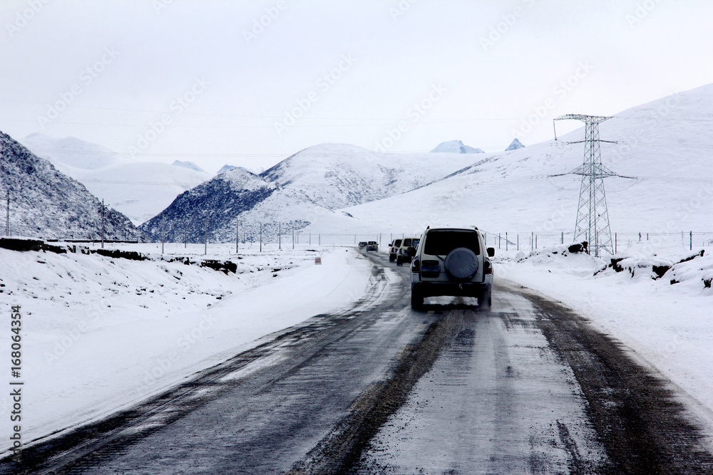 Driving on the road in Tibet, with snow mountain surrounding, no people and wild
