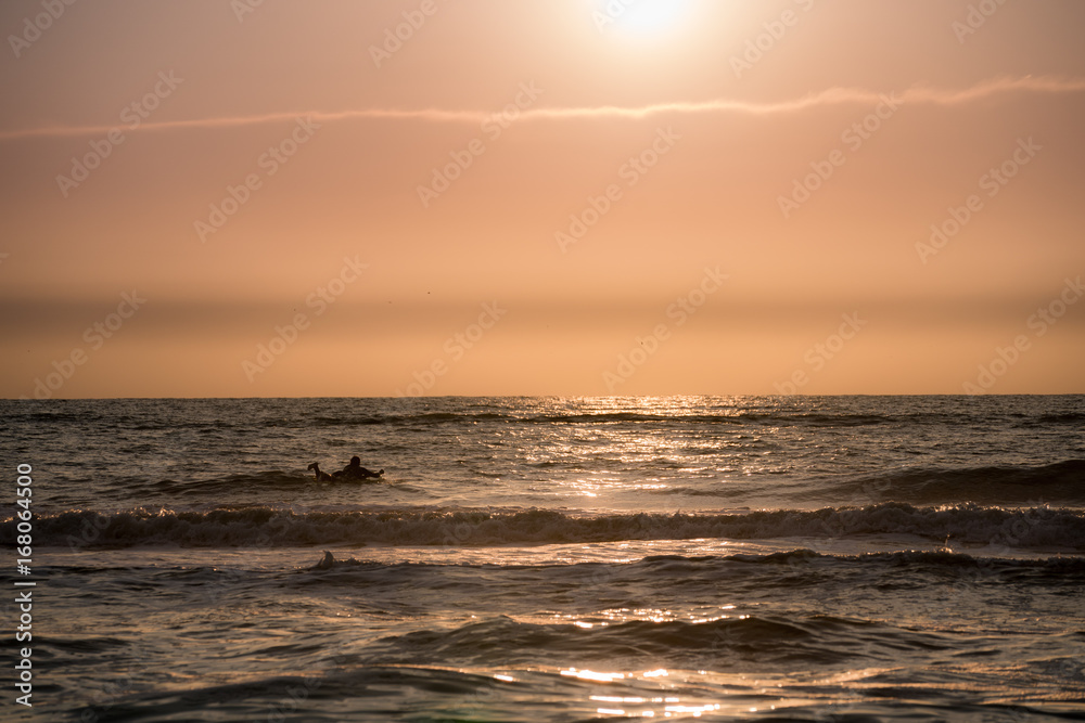 Obraz premium Surfing with the bright orange sun setting 2