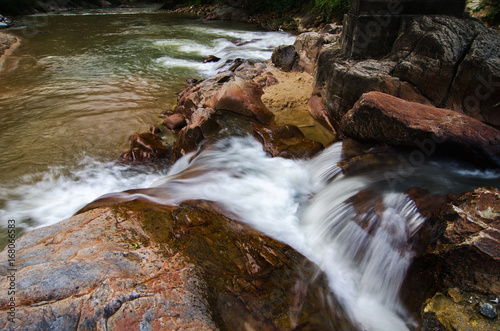 beautiful motion effect of tropical river stream flowing through wet and mossy rock