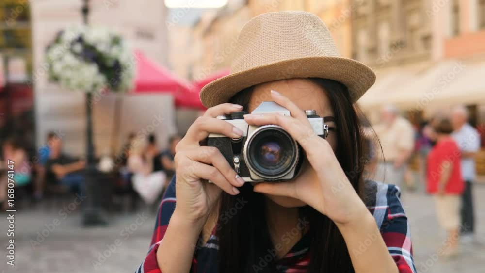 Portrait shot of attractive smiling woman in hat taking pictures on her old vintage camera. Outdoors. Close up Portrait shot of attractive smiling woman in hat taking pictures on her old vintage camera. Outdoors. Close up