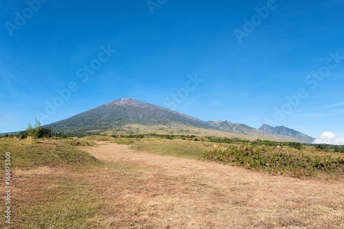 Rinjani mountain and savannah field with blue clear sky..