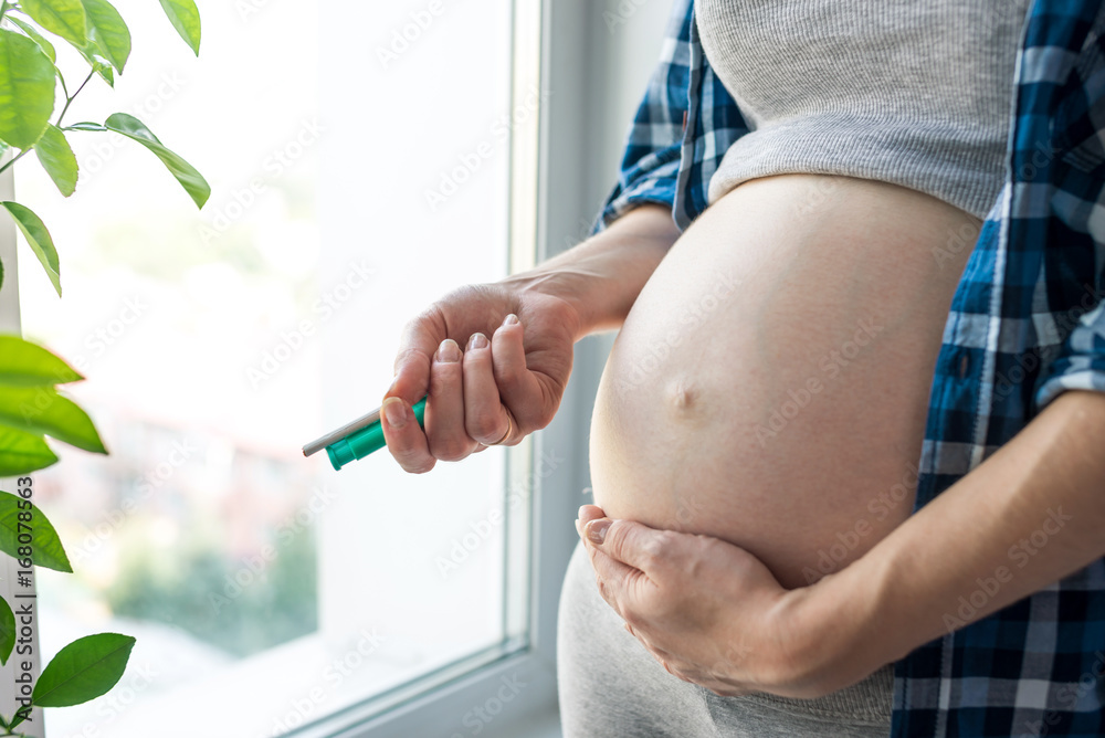 Pregnant woman belly holding a cigarette and a lighter. Concept of Smoking and bad habits during
