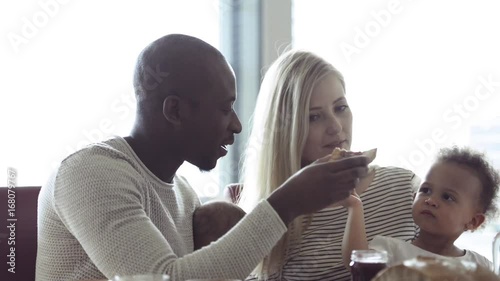 Young interracial family with little children having breakfast.