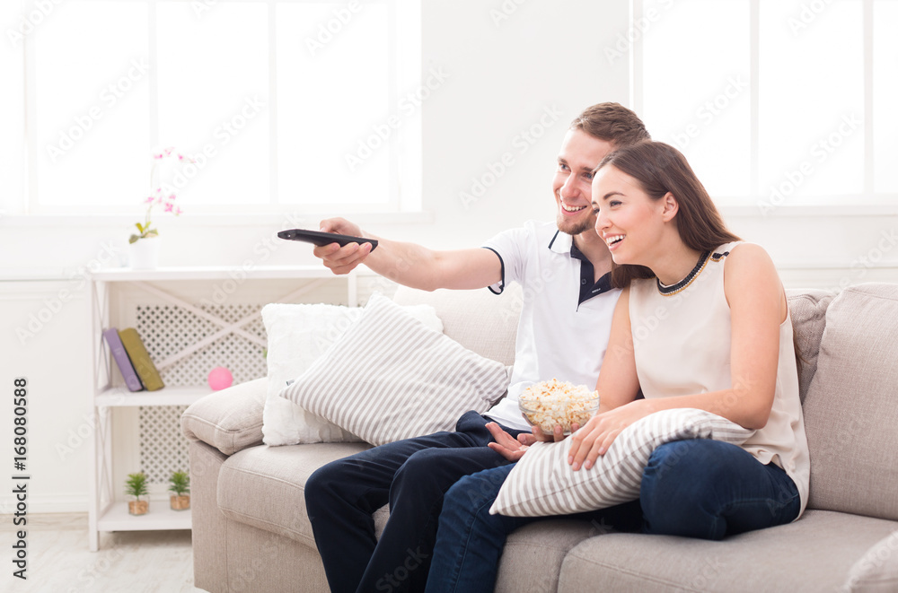 Smiling young couple watching TV at home Smiling young couple watching TV at home