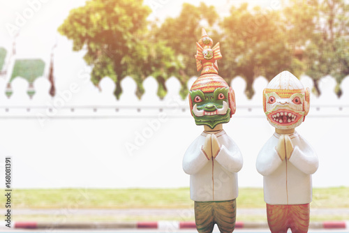 Doll Hanuman and Thotsakan respect hands sawasdee and uniform thai style with image blur wall of temple thailand. photo