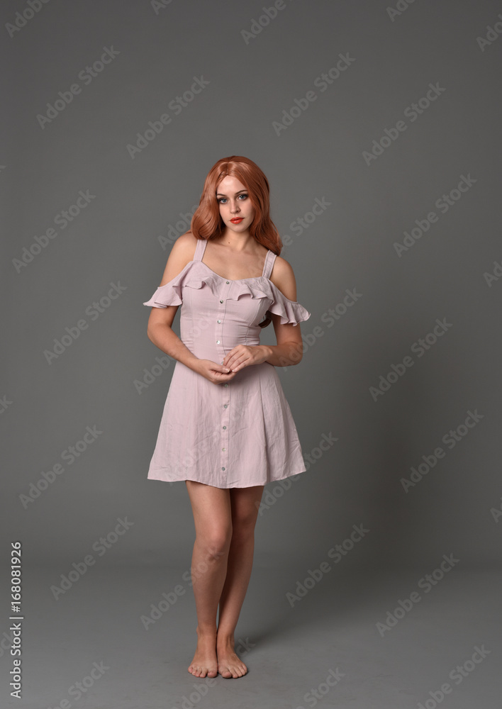 full length portrait of pr a pretty girl wearing simple purple dress, standing pose against a grey background
