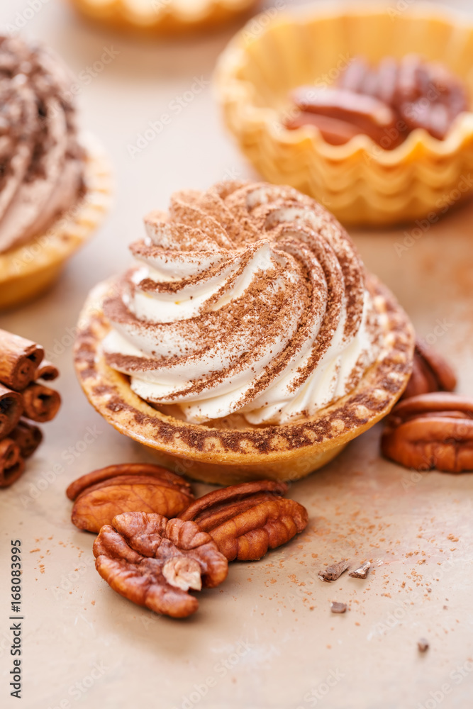 Delicious mini tarts with whipped cream and pecans. Close up. Delicious mini tarts with whipped cream and pecans. Close up.