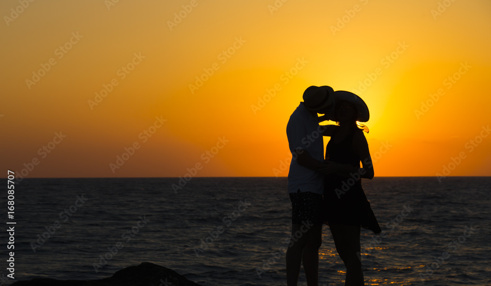 Silhouette of a couple in love on the beach at sunset.Love story.Man and a woman on the beach.Beautiful couple in the sunlight.Silhouettes kissing against the sun.Summer love.Passion.Honeymoon